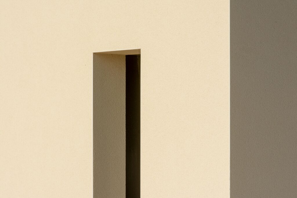 A minimalist architectural facade with geometric shadow patterns and natural light.